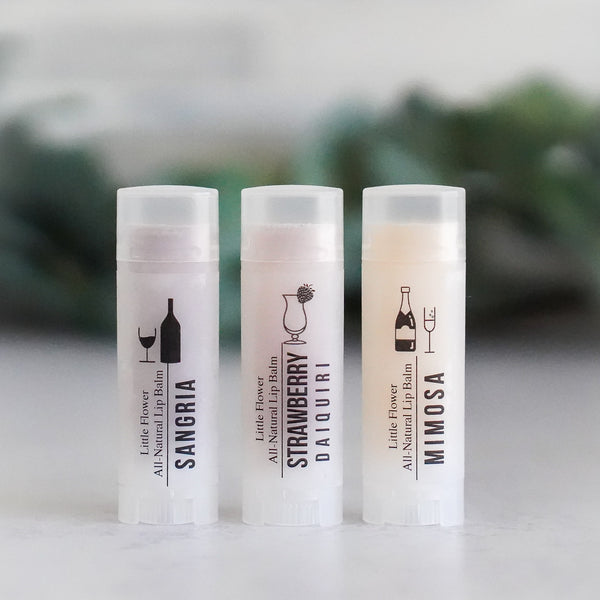 3 lip balms in cocktail flavors including sangria, strawberry daiquiri and mimosa all natural handmade chapsticks in oval tubers with icon graphics of wine, champagne and drinks.  designed as a gift or stocking stuffer for women or party favor for bachelorette party