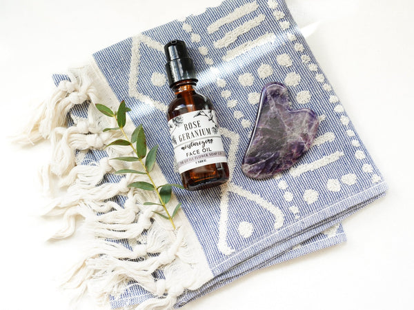 Face oil rose geranium pictured with amathest gua sha facial massage stone