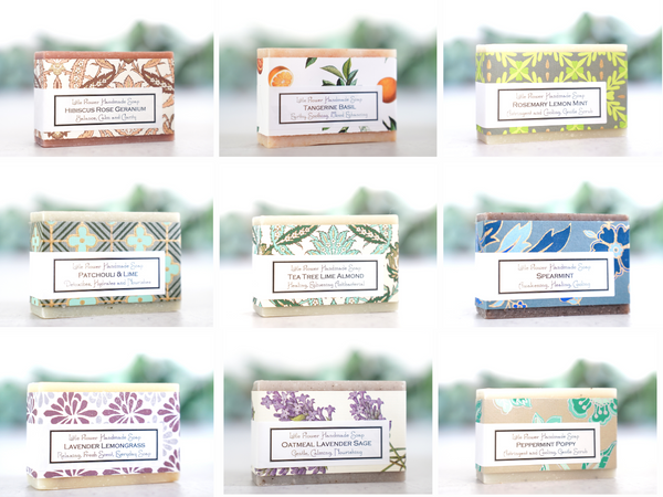 handmade artisan soaps a grid of 9 bars of essential oil natural soaps including hibiscus rose geranium, tangerine basil, rosemary lemon mint, patchouli lime, tea tree lime almond, spearmint, lavender lemongrass, oatmeal lavender sage and peppermint eucalyptus in a rainbow of artisan papers. by the little flower soap co 