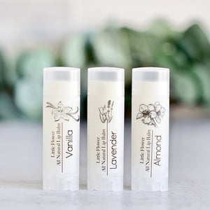 vanilla, lavender and almond chapsticks all natural lip balms handmade by the little flower soap co in beautiful minimalist packaging featuring vintage botanical graphics on a matte clear label on a matte clear oval shaped twist up tube with eucalyptus behind.