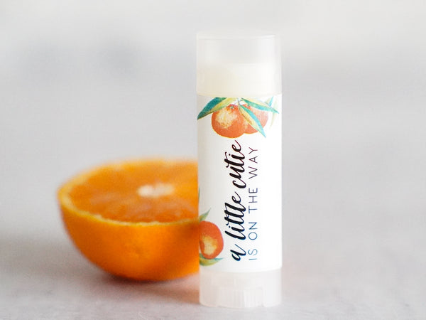 a little cutie is on the way chapstick lip balm for baby shower guest gifts favors or pregnancy announcement.  featuring a botanical watercolor clementine graphic on a white label with black text.  